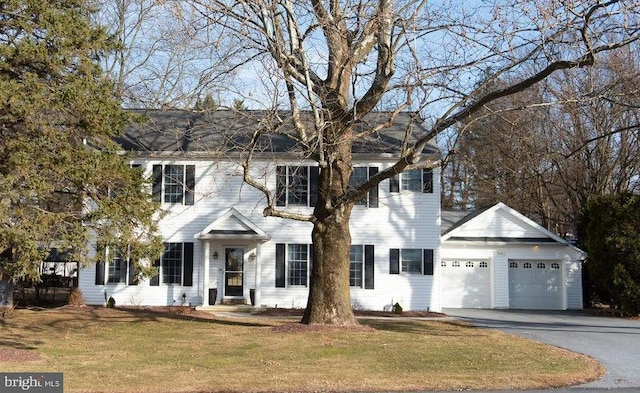 colonial house with an attached garage, a front lawn, and aphalt driveway