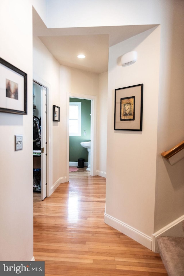 hallway with baseboards, light wood finished floors, and stairs