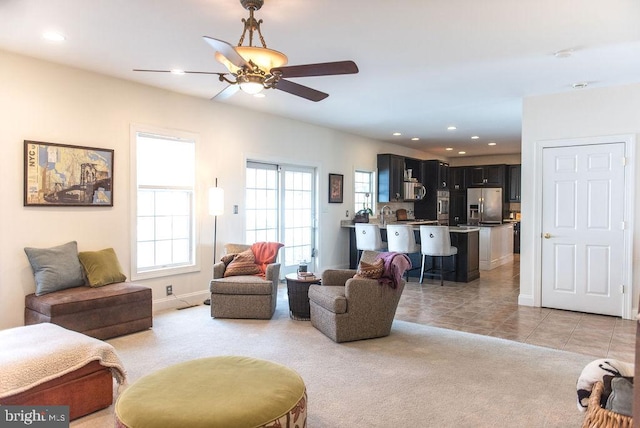 living area with a ceiling fan, recessed lighting, light colored carpet, and light tile patterned flooring