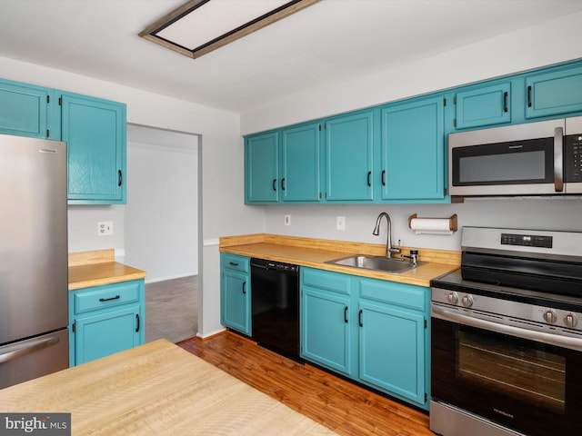 kitchen featuring light countertops, appliances with stainless steel finishes, a sink, and blue cabinets