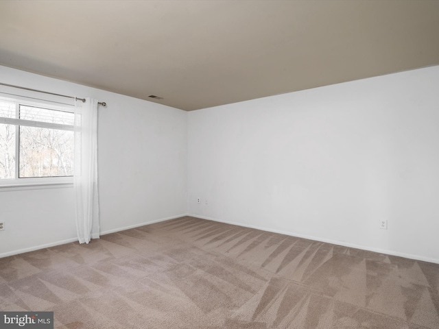 empty room featuring carpet floors, baseboards, and visible vents