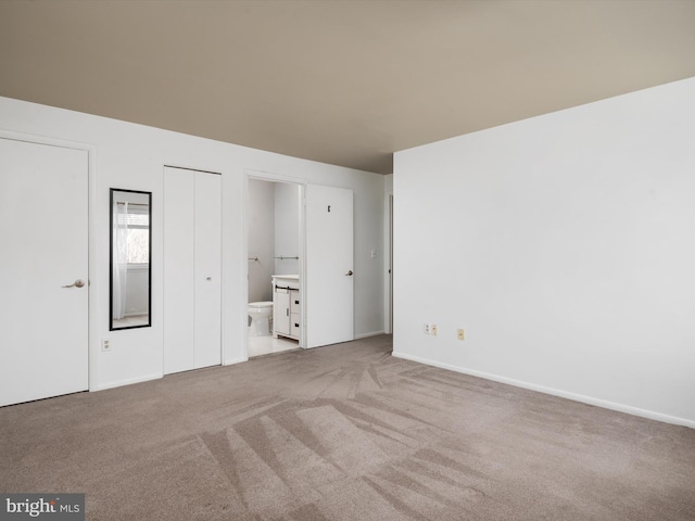 unfurnished bedroom with carpet flooring, connected bathroom, and baseboards