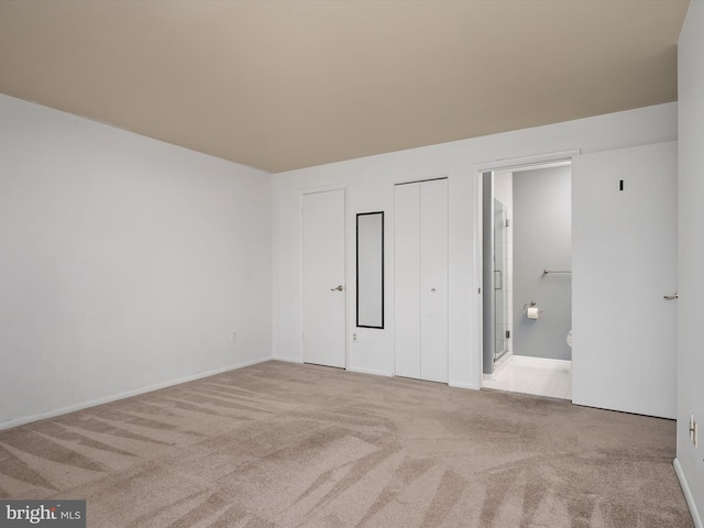 unfurnished bedroom with ensuite bathroom and carpet