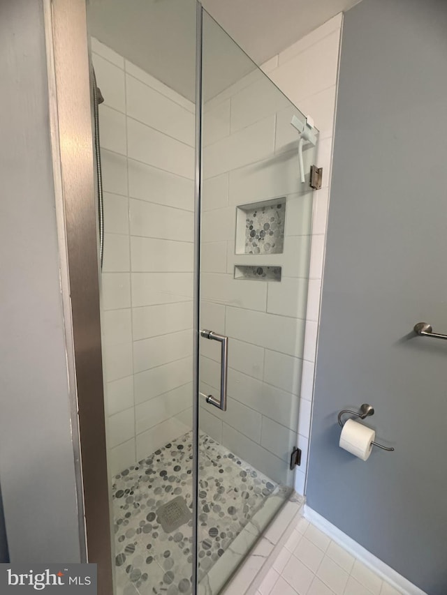 bathroom featuring a stall shower, tile patterned flooring, and baseboards