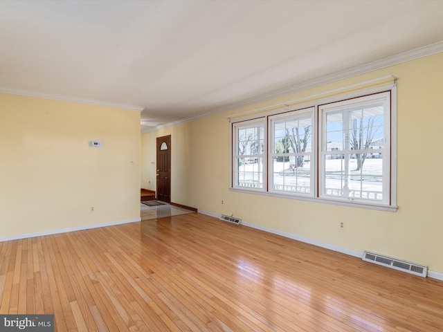 unfurnished living room with visible vents, crown molding, light wood-type flooring, and baseboards