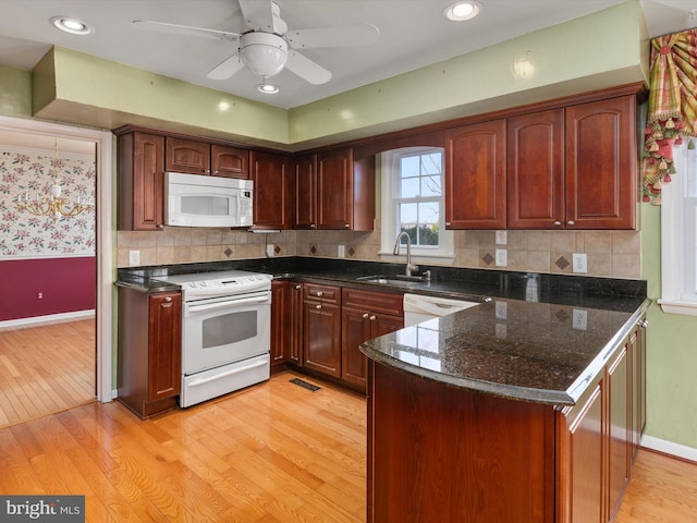 kitchen with a sink, visible vents, white appliances, and light wood-style flooring