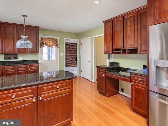 kitchen featuring dark stone countertops, built in study area, light wood-style floors, and stainless steel fridge with ice dispenser