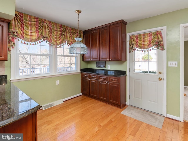 kitchen featuring dark stone countertops, light wood-style flooring, baseboards, and visible vents