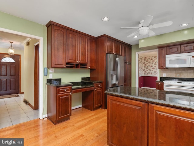 kitchen with white microwave, dark stone counters, light wood-style flooring, recessed lighting, and stainless steel refrigerator with ice dispenser