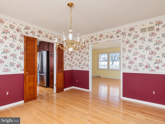 unfurnished room with a wainscoted wall, visible vents, ornamental molding, wallpapered walls, and light wood finished floors