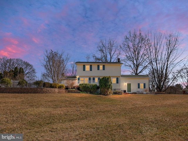 back of house at dusk featuring a yard