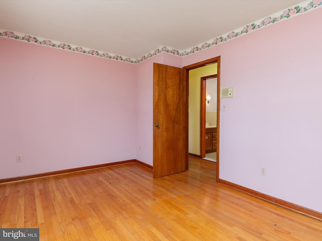 spare room featuring baseboards and light wood-style floors