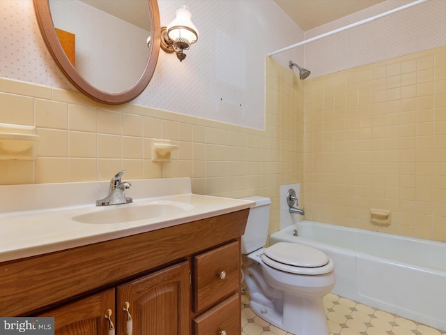 bathroom featuring wallpapered walls, shower / bathing tub combination, toilet, and a wainscoted wall