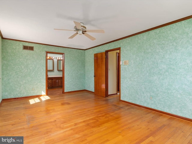 empty room featuring visible vents, wallpapered walls, and crown molding