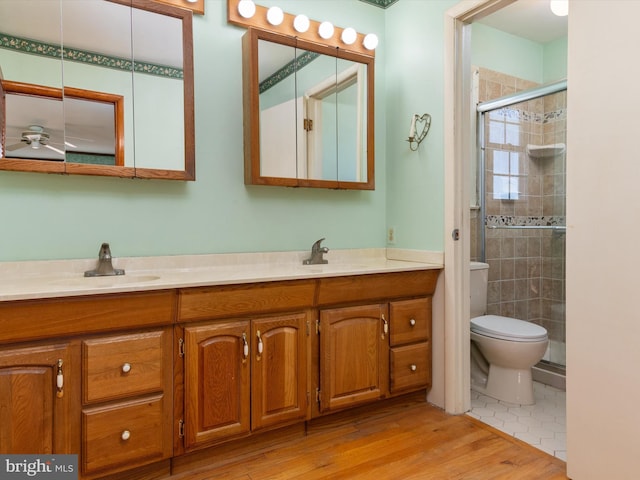 full bath featuring double vanity, a shower stall, toilet, and a sink