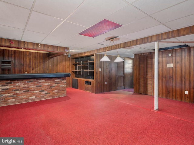 interior space featuring carpet flooring, wood walls, a dry bar, and a paneled ceiling