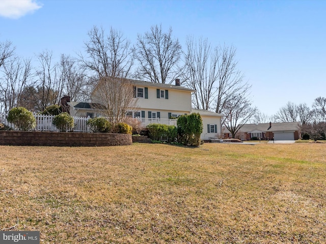 back of house with a lawn, a chimney, and fence