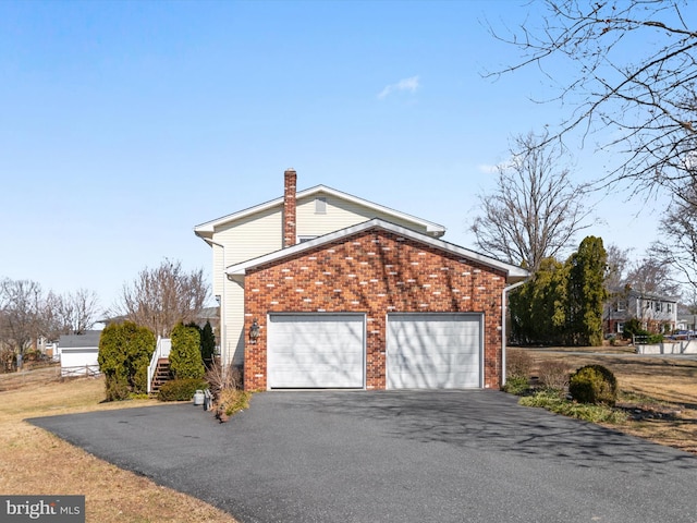 view of property exterior featuring brick siding, a chimney, and driveway