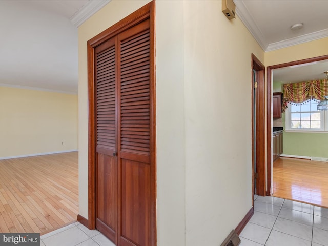 hall with light tile patterned floors, baseboards, and ornamental molding