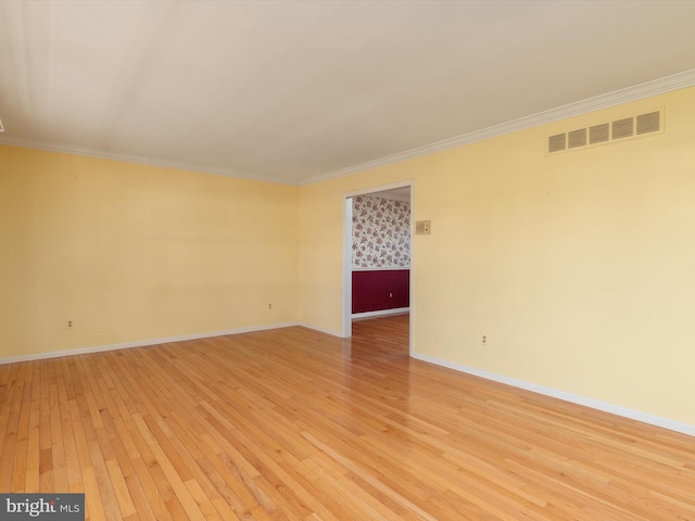 unfurnished room with visible vents, light wood-style flooring, baseboards, and ornamental molding