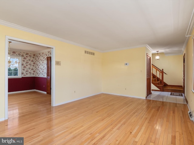 empty room with visible vents, wallpapered walls, ornamental molding, stairs, and light wood-type flooring