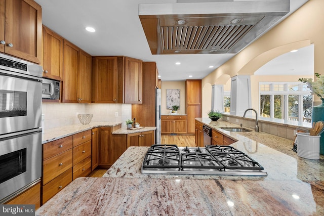 kitchen with extractor fan, brown cabinets, appliances with stainless steel finishes, and a sink