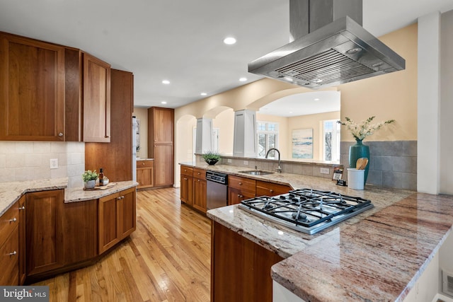 kitchen with a sink, brown cabinets, appliances with stainless steel finishes, and island range hood