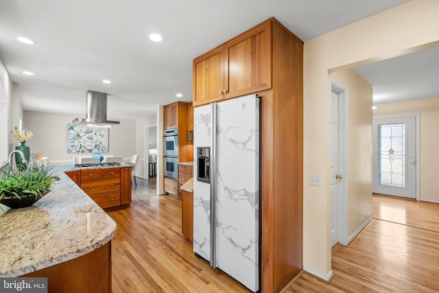 kitchen featuring light wood-style flooring, exhaust hood, brown cabinets, and appliances with stainless steel finishes