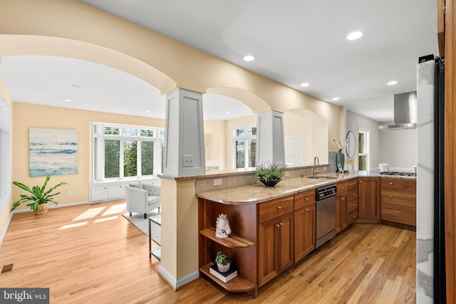 kitchen with light wood-type flooring, stainless steel appliances, light stone countertops, and brown cabinets