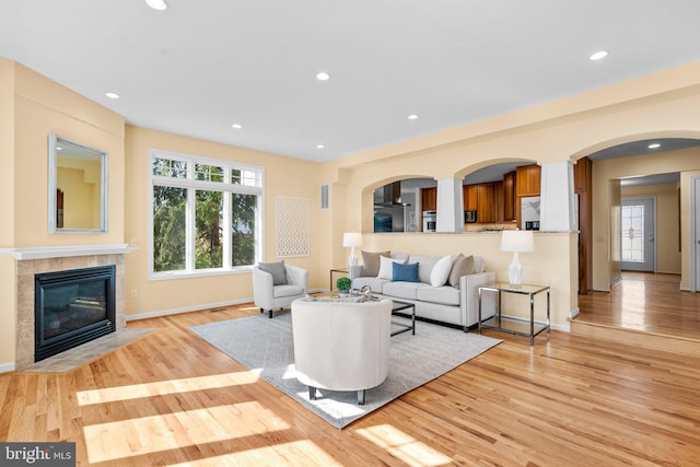 living room with light wood finished floors, recessed lighting, and a tile fireplace