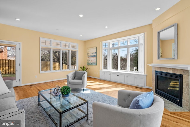 living area with recessed lighting, light wood-type flooring, and a tile fireplace