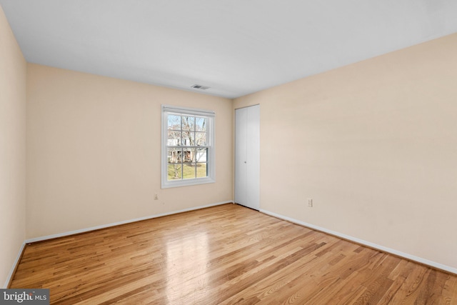 empty room with visible vents, baseboards, and light wood-style floors