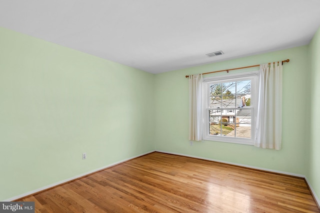 spare room featuring visible vents, baseboards, and wood finished floors