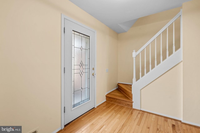 foyer entrance with stairway, baseboards, and light wood-type flooring