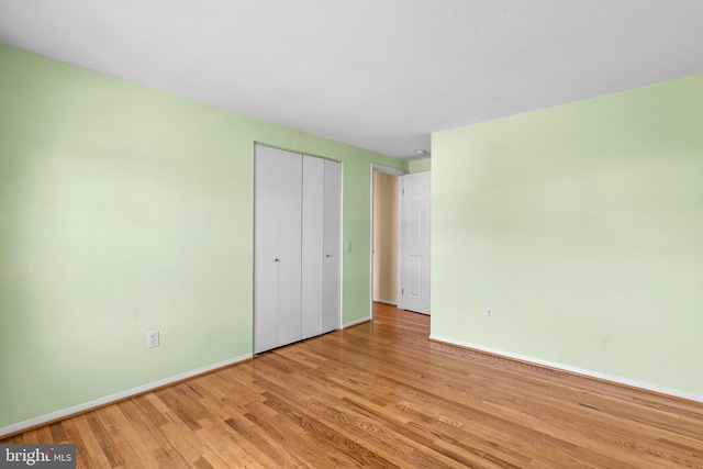 unfurnished bedroom with a closet, baseboards, and wood finished floors