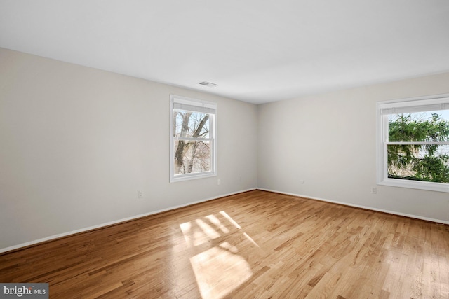 empty room featuring visible vents, baseboards, and wood finished floors