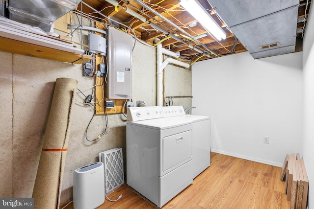 washroom with visible vents, washer and clothes dryer, electric panel, laundry area, and light wood-style floors