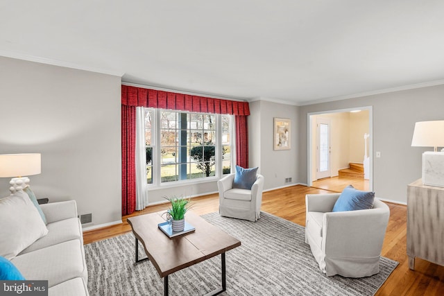 living area with visible vents, crown molding, baseboards, and wood finished floors