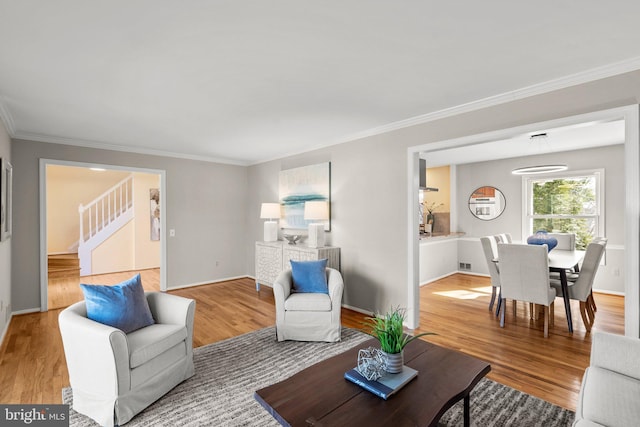 living area with crown molding, stairs, and wood finished floors