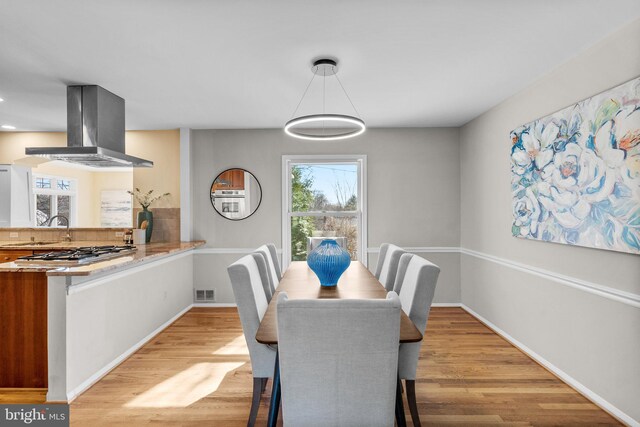 dining area with light wood-style flooring, baseboards, and visible vents