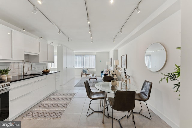 dining space featuring light tile patterned floors, rail lighting, and baseboards