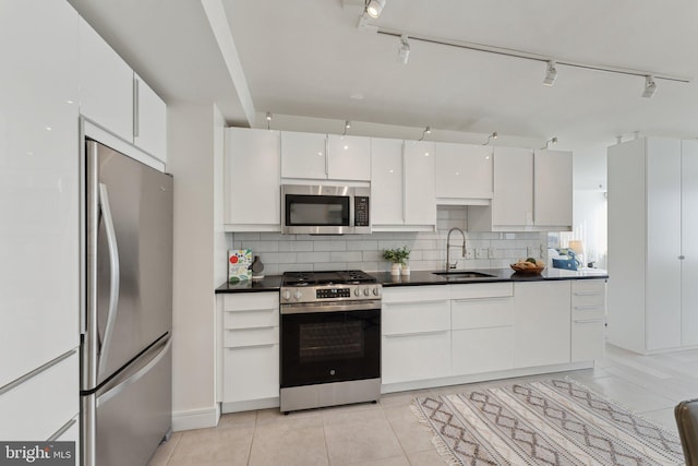 kitchen featuring decorative backsplash, dark countertops, appliances with stainless steel finishes, and a sink