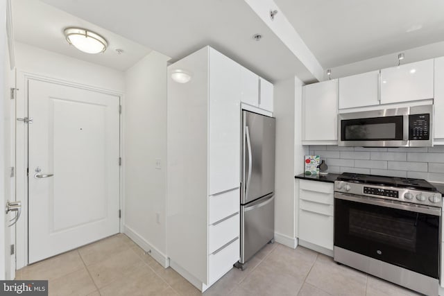 kitchen featuring light tile patterned floors, white cabinets, appliances with stainless steel finishes, and backsplash