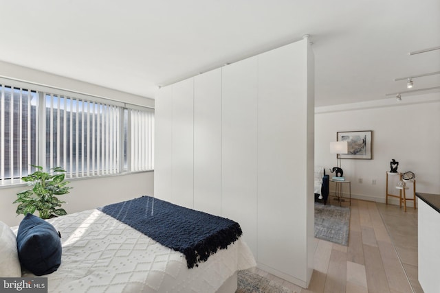 bedroom with rail lighting and light wood-type flooring