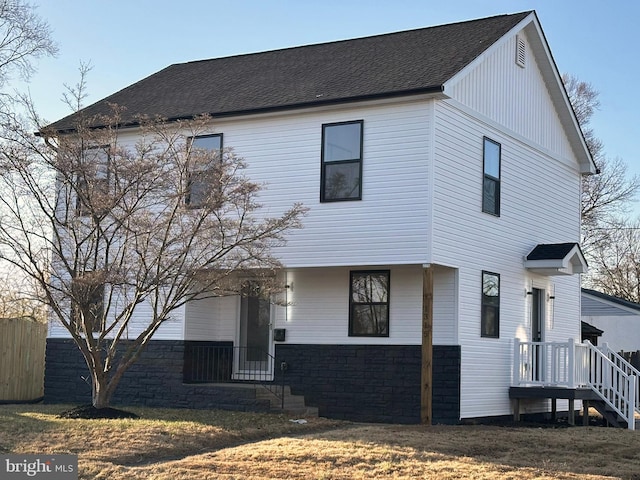 view of front facade with a shingled roof and fence