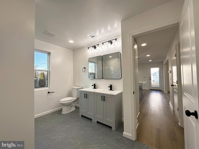 bathroom with toilet, a wealth of natural light, visible vents, and a sink