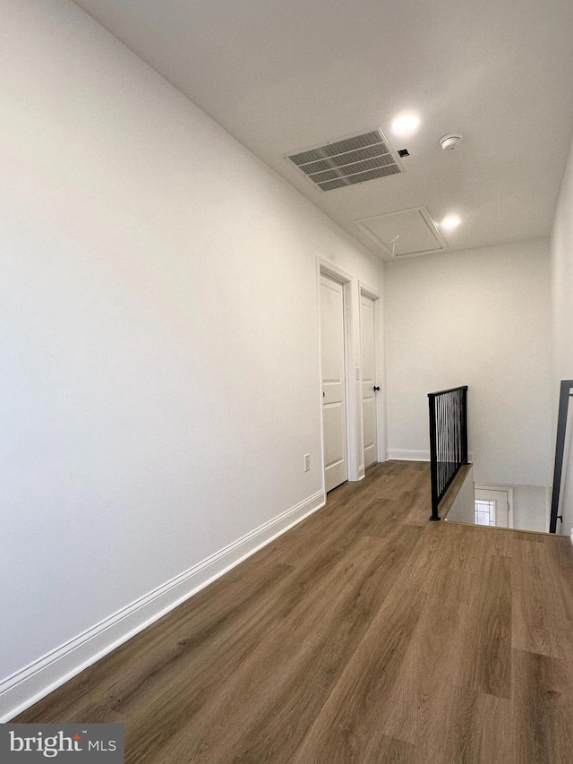 empty room featuring visible vents, wood finished floors, attic access, and baseboards