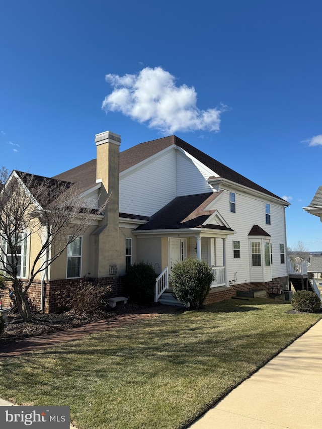 view of front of home with a front lawn, a chimney, and brick siding