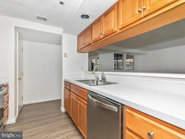 kitchen with light wood-type flooring, a sink, stainless steel appliances, light countertops, and baseboards