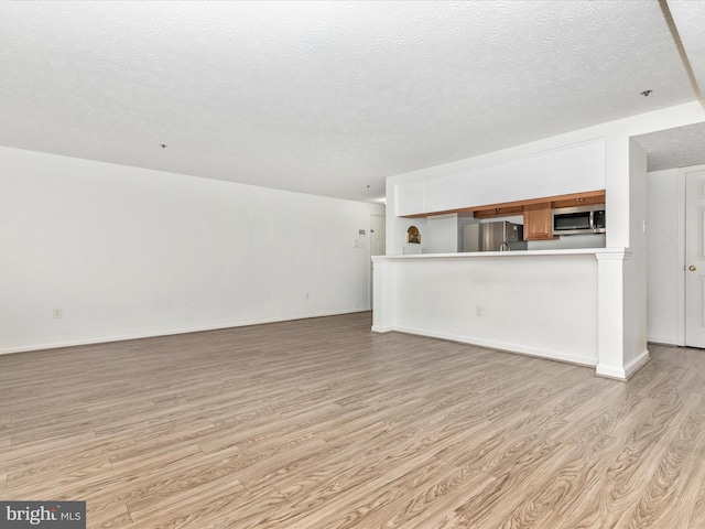 unfurnished living room featuring light wood-style flooring and a textured ceiling